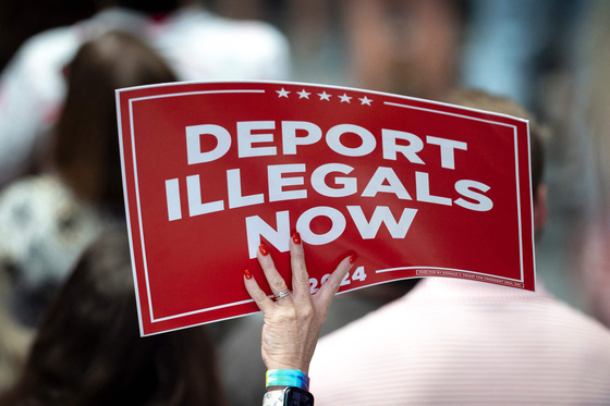 A supporter of Donald Trump holds up a sign reading ″deport illegals now″ during a campaign rally at the Bojangles Coliseum in Charlotte, North Carolina, on July 24, 2024. [YONHAP/AFP]