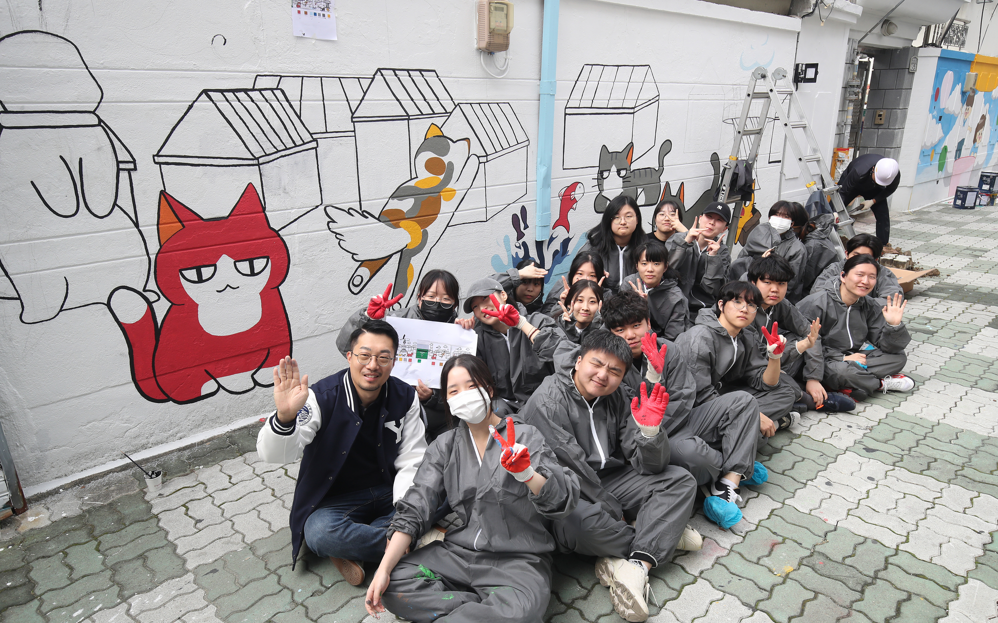Webtoonists and students pose for a photo after painting the wall together as part of a volunteer activity on Oct. 29 in Daegu. [NEWS1]