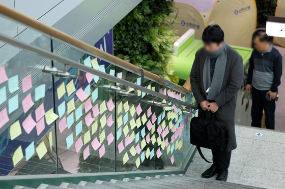 A person reads messages honoring the victims of Jeju Air crash posted on a staircase in Muan International Airport in Muan, South Jeolla, on Friday. [YONHAP]