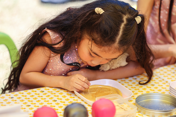 A child from the Philippines makes dalgona in Seongbuk district, northern Seoul, on May 21, 2024. [YONHAP]