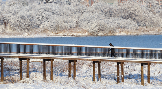 A pedestrian crosses a bridge covered in snow in Jeonju, South Jeolla, on Jan. 8. [YONHAP]