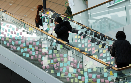 Sticky notes with messages to victims from bereaved relatives are posted on glass along the stairs in Muan International Airport in South Jeolla on Jan. 6. [YONHAP] 