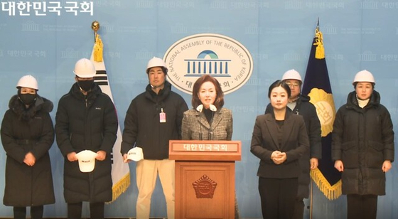 Conservative People Power Party Rep. Kim Meen-geon, center, introduces the Anti-communist Youth Group at the National Assembly in Yeouido, western Seoul on Jan. 9. Kim Jung-hyun, leader of the group, third from the left, stands wearing a white helmet. [SCREEN CAPTURE]