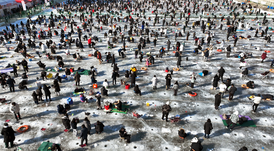Participants at the Hwacheon Sancheoneo Ice Festival fish for mountain trout through a frozen stream in Hwacheon County, Gangwon, on Jan. 12. [NEWS1]
