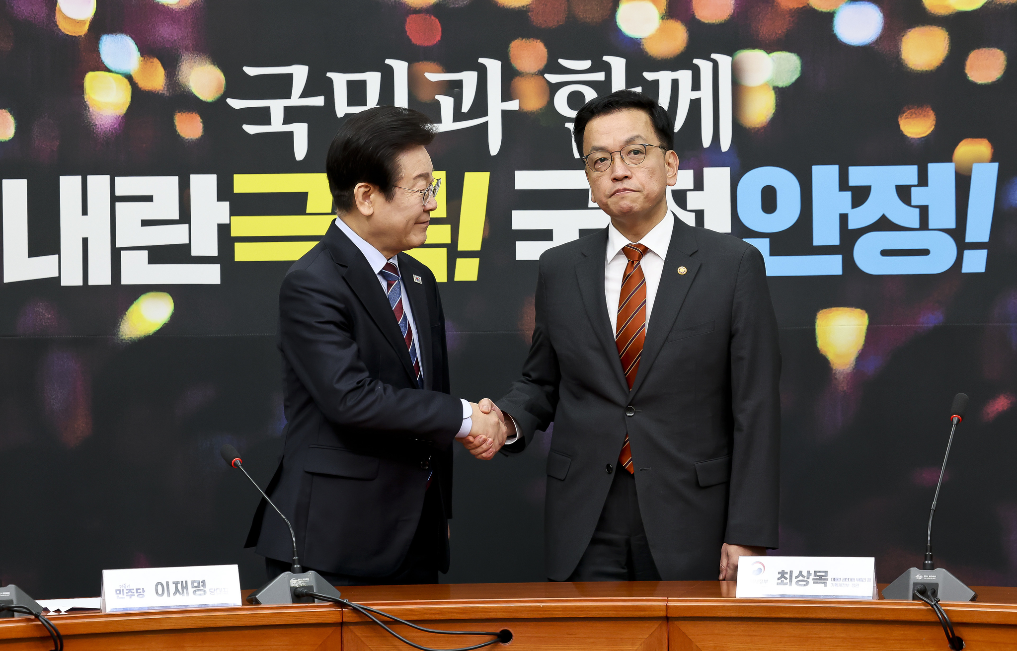 Democratic Party leader Lee Jae-myung, left, smiles and he shakes hands with acting President Choi Sang-mok at the National Assembly in Yeouido, western Seoul, on Jan. 13. [NEWS1]