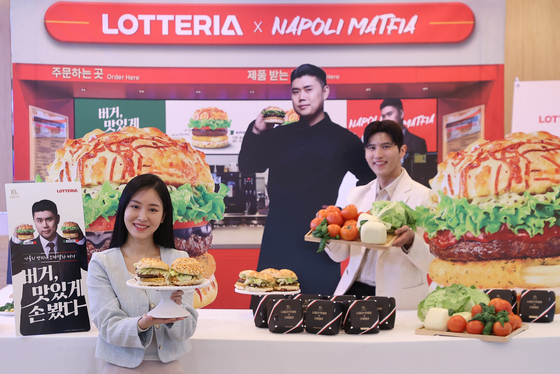 Models introduce the new Napoli Matfia Mozzarella Burger at a Lotteria branch near Sookmyung Women's University Station in Yongsan District, central Seoul, on Jan. 16. [YONHAP]