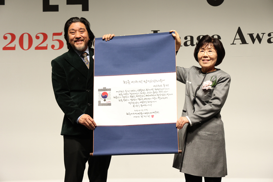 Chef Edward Lee, left, receives an award from President of Corea Image Communication Institute Choi Jung Hwa, at the Korea Image Awards on Wednesday at Grand InterContinental Seoul Parnas in Gangnam District, southern Seoul. [COREA IMAGE COMMUNICATION INSTITUTE] 