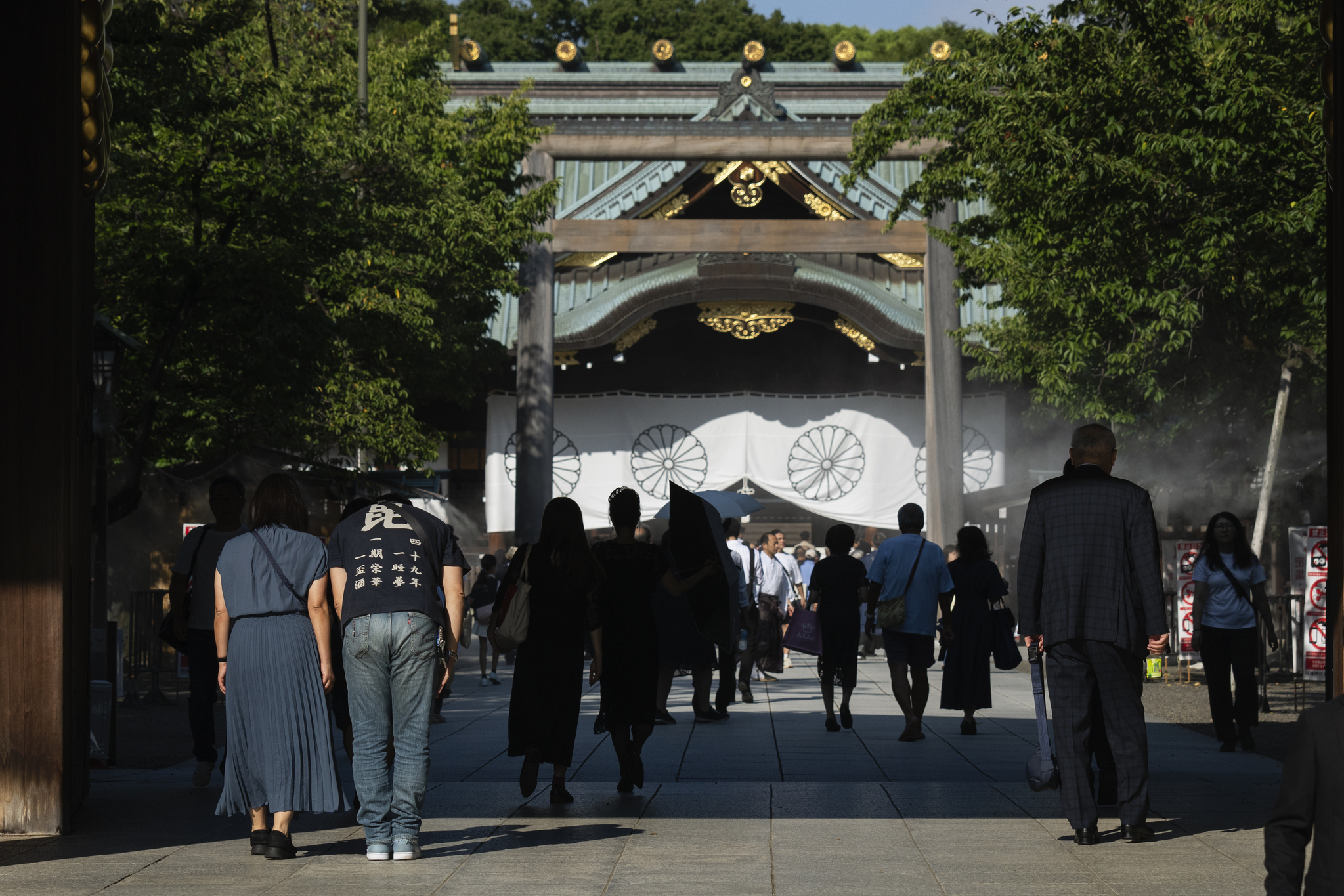 A woman and a man bow in front of the main hall of Yasukuni Shrine in Tokyo on Aug. 15, 2024. [AP/YONHAP]