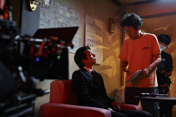 A behind-the-scenes still from season two of Netflix's ″Squid Game″ (2021-) showing actor Gong Yoo sitting on a pink sofa [NETFLIX]