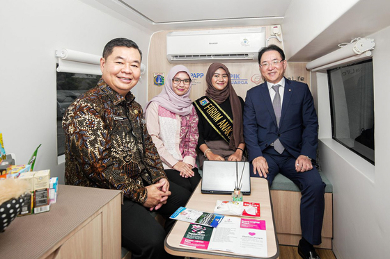Acting Jakarta Gov. Teguh Setyabudi, far left, and Hanhwa Life Senior Executive Vice President Hong Jeong-pyo, far right, pose for a photo inside a mobile Family Center service vehicle on Jan. 16. [HANWHA LIFE] 