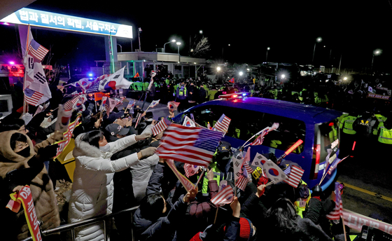 Supporters of impeached President Yoon Suk Yeol, left, cheer as a convoy carrying Yoon returns to the Seoul Detention Center in Uiwang, Gyeonggi, after his arrest warrant hearing at the Seoul Western District Court on Jan. 18. [JOINT PRESS CORPS]