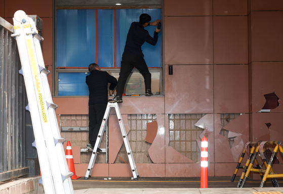 Workers repair damaged windows of the Seoul Western District Court in Mapo District on Jan. 20. [YONHAP]