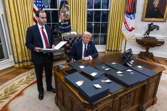 President Donald Trump, right, signs numerous executive orders, including pardons for participants in the Jan. 6 riots and a delay on the TikTok ban, on the first day of his presidency in the Oval Office of the White House in Washington on Jan. 20. [UPI/YONHAP]