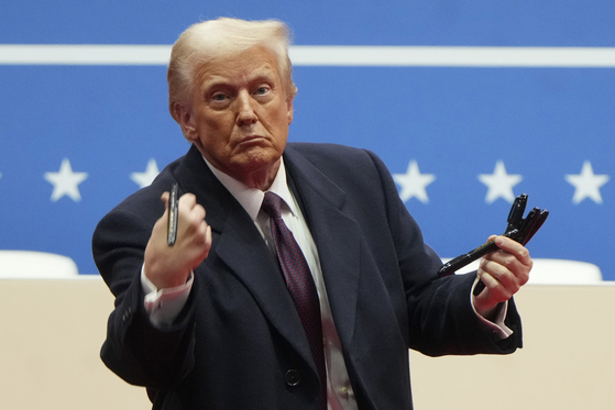 U.S. President Donald Trump throws pens used to sign executive orders to the crowd during an indoor Presidential Inauguration parade event in Washington, Jan. 20. [AP/YONHAP]