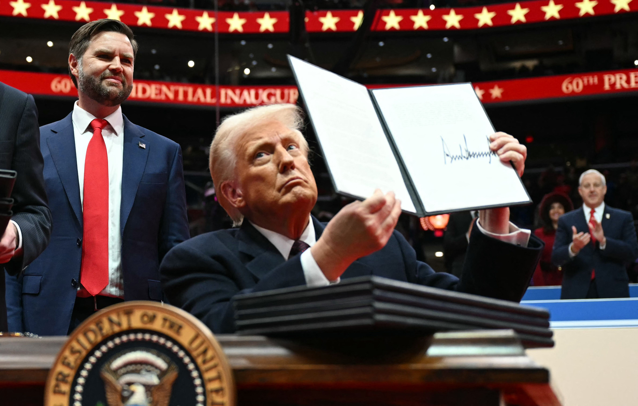 U.S. President Donald Trump holds an executive order he just signed during the inaugural parade inside Capital One Arena, in Washington, DC, on Jan. 20. [AFP/YONHAP]