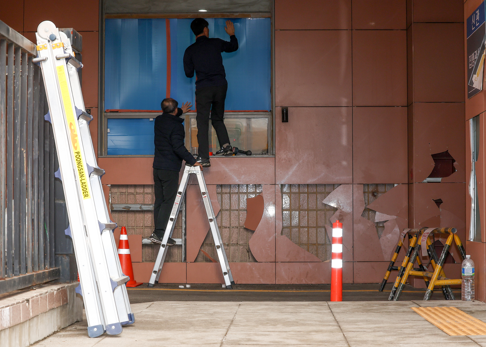 Workers repair a broken window at the Seoul Western District Court on Jan. 20, following vandalism by angry protesters the previous day. [YONHAP]