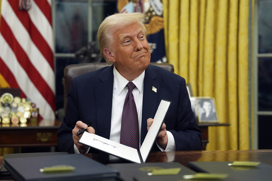U.S. President Donald Trump signs executive orders in the Oval Office of the White House in Washington, Jan. 20. [AP/YONHAP]