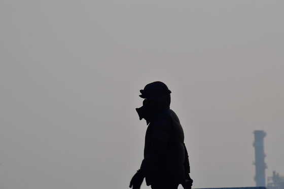 A person wearing a mask walks along the beach in Pohang, North Gyeongsang, on Jan. 22. [NEWS1]