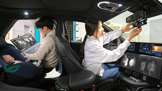 Hyundai Mobis employees demonstrate an in-cabin monitoring system that analyzes drivers' biosignals to detect any risk conditions. [HYUNDAI MOBIS] 