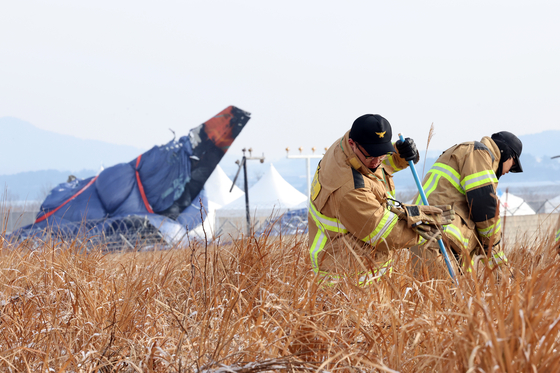 Firefighters conduct search operations near the Jeju Air crash site at Muan International Airport on Jan. 11. [YONHAP]