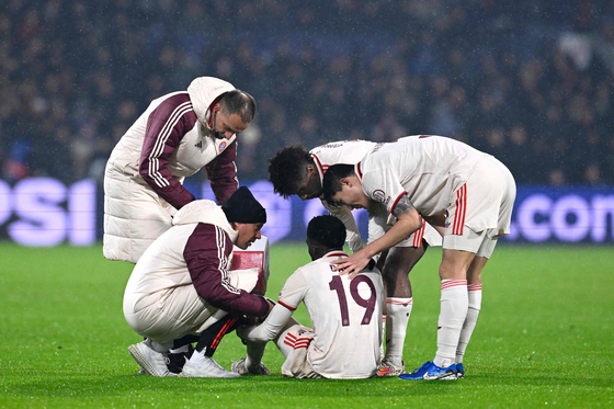 Bayern Munich players and physio's comfort Canadian defender Alphonso Davies after injury during the UEFA Champions League football match between Feyenoord and Bayern Munich at the Feyenoord Stadium in Rotterdam, Netherlands on Jan. 22. [AFP/YONHAP]