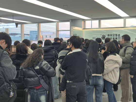 Passengers at Gimhae Airport wait to register their passports and biometric information at a registration desk on Jan. 17. Passengers who preregister their passports, faces and palms can be screened more quickly at a counter that is open just for registered users. [KIM MIN-JU]