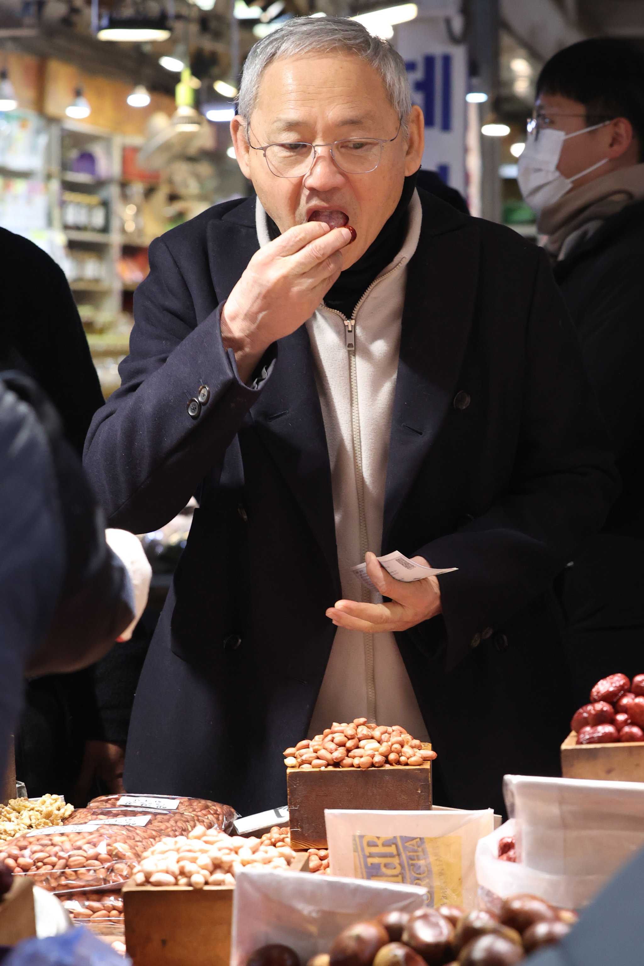 Culture Minister Yu In-chon tries a dried date at Gyeongdong Market in central Seoul on Friday. [MINISTRY OF CULTURE, SPORTS AND TOURISM] 