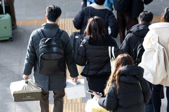 People holding their luggage walk down the stairs at Seoul Station in central Seoul on Jan. 26, the second day of the Lunar New Year holiday. [NEWS1]