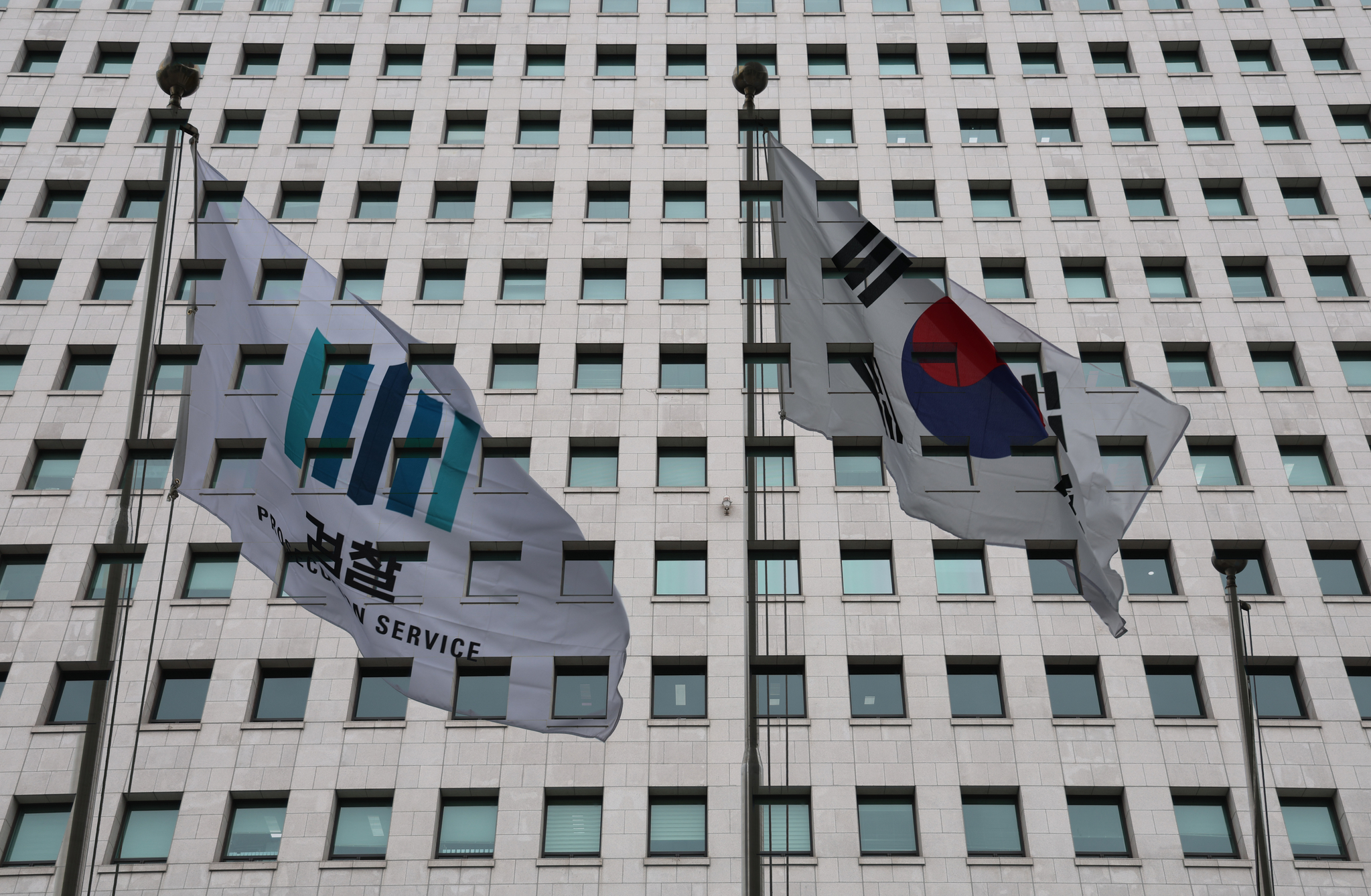 The Korean national flag, right, and a banner with the logo of the state prosecution service flutter outside the Supreme Prosecutors' Office in Seocho District, southern Seoul, on Jan. 26. [NEWS1]