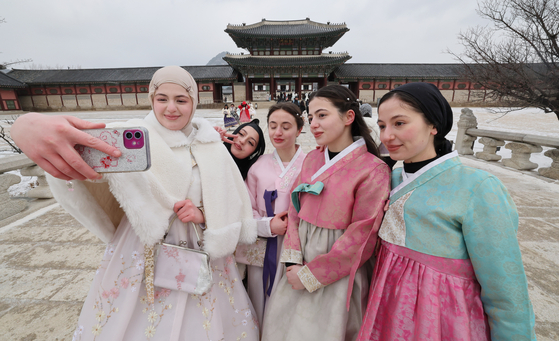 Tourists in hanbok, or traditional Korean dress, take selfies near Gyeongbok Palace in Jongno District, central Seoul, on Jan. 28. [NEWS1] 