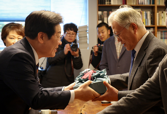 Lee Jae-myung, leader of the Democratic Party, left, presents a gift to former President Moon Jae-in in Moon's residence in South Gyeongsang, on Jan. 30. [DEMOCRATIC PARTY]