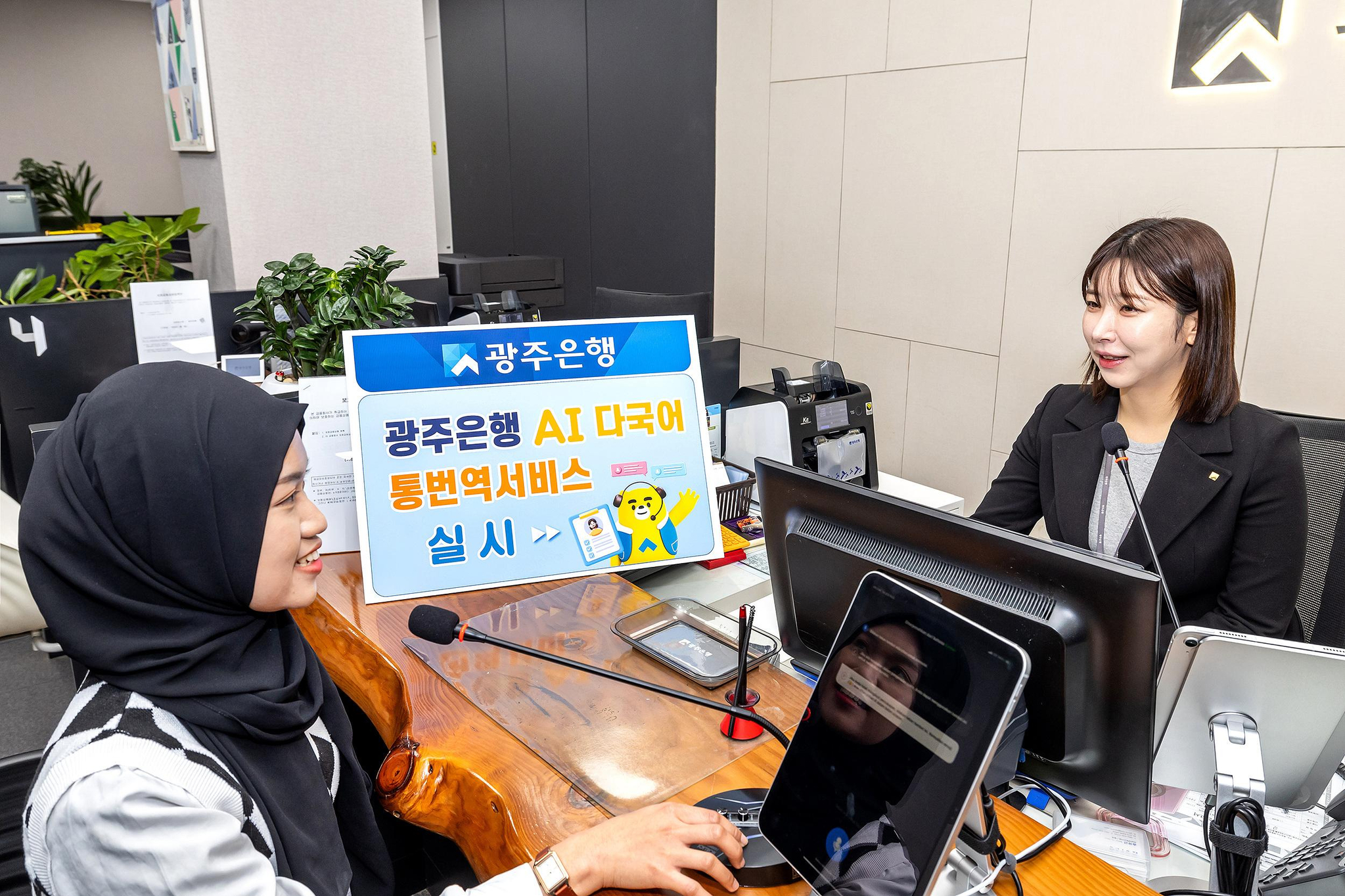 A bank teller and customer talk to each other at a Kwangju Bank branch using the new real-time translation service. [KWANGJU BANK]
