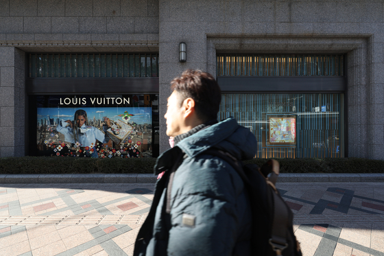 A pedestrian walks by a row of luxury good stores at a department store in Seoul on Jan. 2. [YONHAP] 