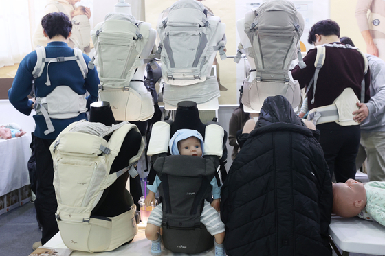 Attendees try on baby carriers at the 47th Befe Baby Fair at Coex in southern Seoul. [YONHAP]