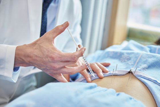 A traditional medicine doctor administers pharmacopuncture in this stock photo. [GETTY IMAGES BANK]