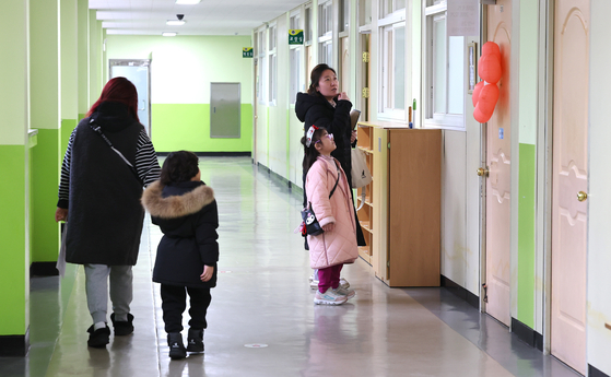 Parents and their kids take a look around an elementary school in Incheon on Jan. 7 before the new semester starts in March. [YONHAP]