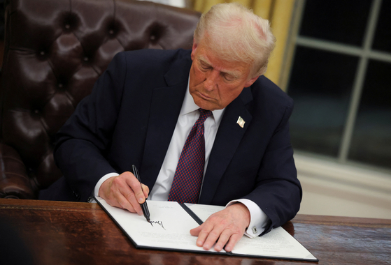 U.S. President Donald Trump signs documents as he issues executive orders and pardons for January 6 defendants in the Oval Office at the White House on Inauguration Day in Washington, U.S., January 20, 2025. [REUTERS/YONHAP]