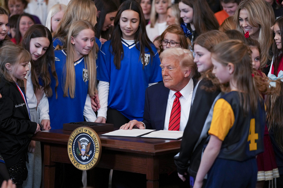 President Donald Trump signs an executive order aimed at prohibiting transgender women and girls from competing in women’s sports, in the East Room at the White House in Washington, on Wednesday, Feb. 5, 2025. President Trump signed the executive order on National Girls and Women in Sports Day, directing agencies to withdraw federal funding for any schools that refused to comply. (Eric Lee/The New York Times)