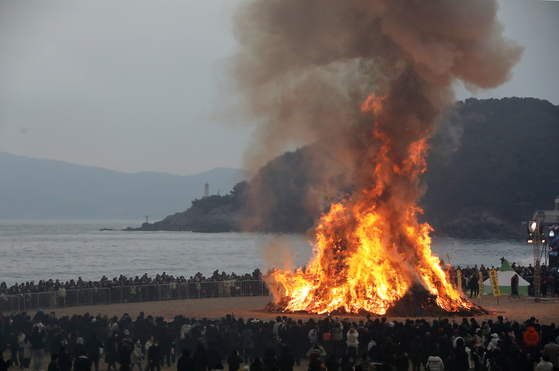 People circle around to watch the burning dalgip, or “moon house,” in Haeundae District, Busan, on Feb. 12, to mark Jeongwol Daeboreum, a traditional holiday celebrating the first full moon after the Lunar New Year. [NEWS1]