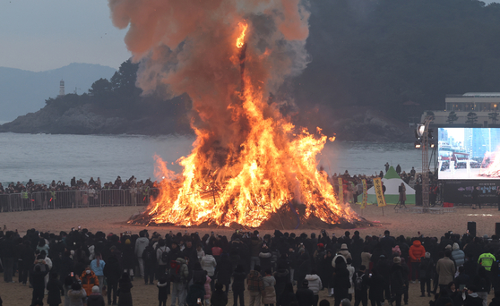 People circle around to watch the burning dalgip, or “moon house,” in Haeundae District, Busan, on Feb. 12, to mark Jeongwol Daeboreum, a traditional holiday celebrating the first full moon after the Lunar New Year. [YONHAP]