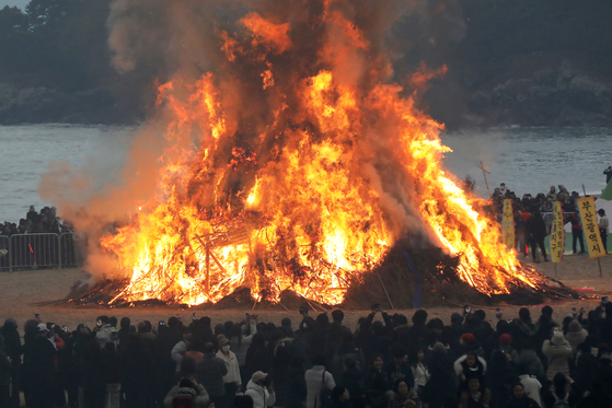 People circle around to watch the burning dalgip, or “moon house,” in Haeundae District, Busan, on Feb. 12, to mark Jeongwol Daeboreum, a traditional holiday celebrating the first full moon after the Lunar New Year. [NEWS1]