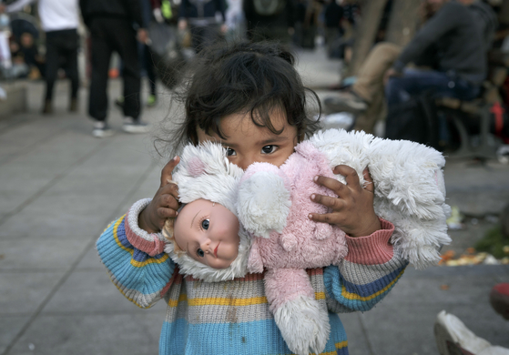 A child of a migrant family clutches a doll in Athens on Feb. 29, 2016. [AP]
