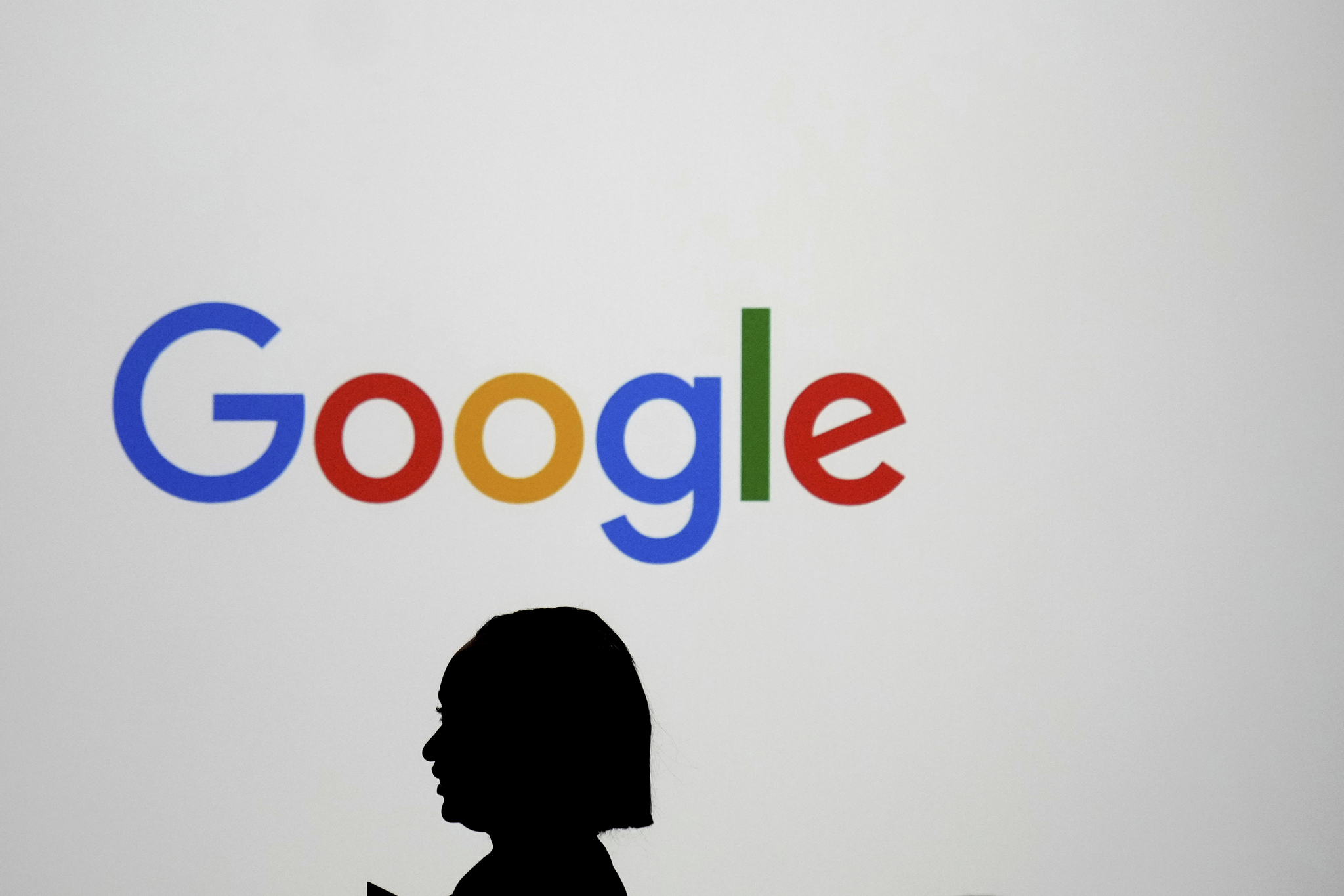 A woman walks by a giant screen with a Google logo at an event at the Paris Google Lab on the sidelines of the AI Action Summit in Paris on Feb. 9. [AP]