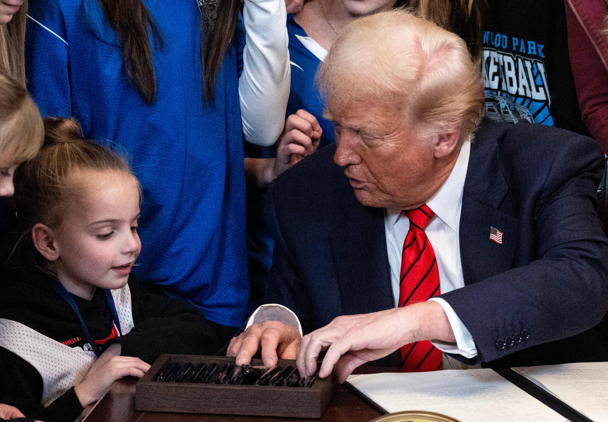 U.S. President Donald Trump speaks with a child as he selects a pen to sign the No Men in Women's Sports Executive Order in the East Room of the White House in Washington, DC, on Feb. 5. [AFP]