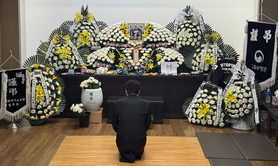 Father whose daughter was stabbed to death sits down and stares at a picture of his daughter, identified as Kim Ha-neul, during a funeral service held in Daejeon on Feb. 12. [NEWS1]