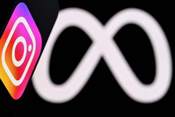 U.S. social network Instagram's logo is displayed on a smartphone in front of the media giant Meta's logo on a laptop screen in this photo illustration created on Jan. 9 in Frankfurt am Main, western Germany. [AFP/YONHAP]