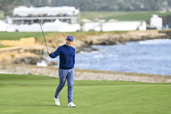 Rory McIlroy raises his putter to fans as he celebrates his two stroke victory on the 18th hole green during the final round of the AT&T Pebble Beach Pro-Am at Pebble Beach Golf Links on Feb. 2, in Pebble Beach, California. [GETTY IMAGES]