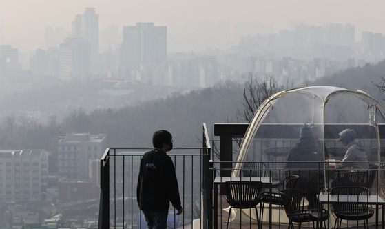 People on a rooftop in Jongno District, central Seoul, gaze upon buildings shrouded in smog on the morning of Feb. 16, when ultrafine dust enveloped most of the nation in a gray haze. The Korea Meteorological Administration said ultrafine dust levels will gradually drop into the night, starting with the Seoul metropolitan area. [YONHAP]