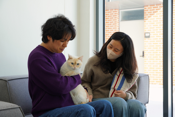 Yoo Dong-jin, left, hugs Ppuppu the cat as his wife watches on Feb. 7. [SON SUNG-BAE]