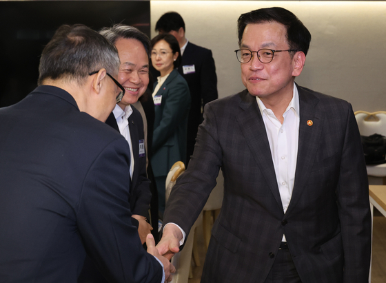 Acting President Choi Sang-mok, right, shakes hands with an attendant at a meeting with representatives of companies aimed at exploring ways to promote the culture of balancing work and family life at the government complex in central Seoul on Feb. 17. [YONHAP] 
